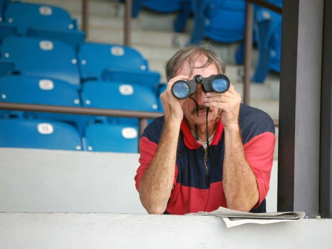 Mann schaut in einem Stadion durch ein Fernglas.